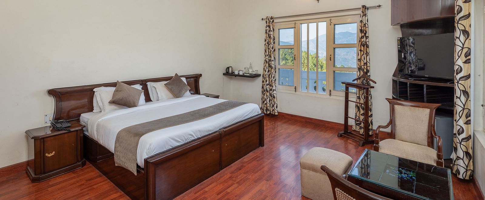 Shot of a spacious guest room at DLS Tehri Club Resort with a king size bed and a sitting area.